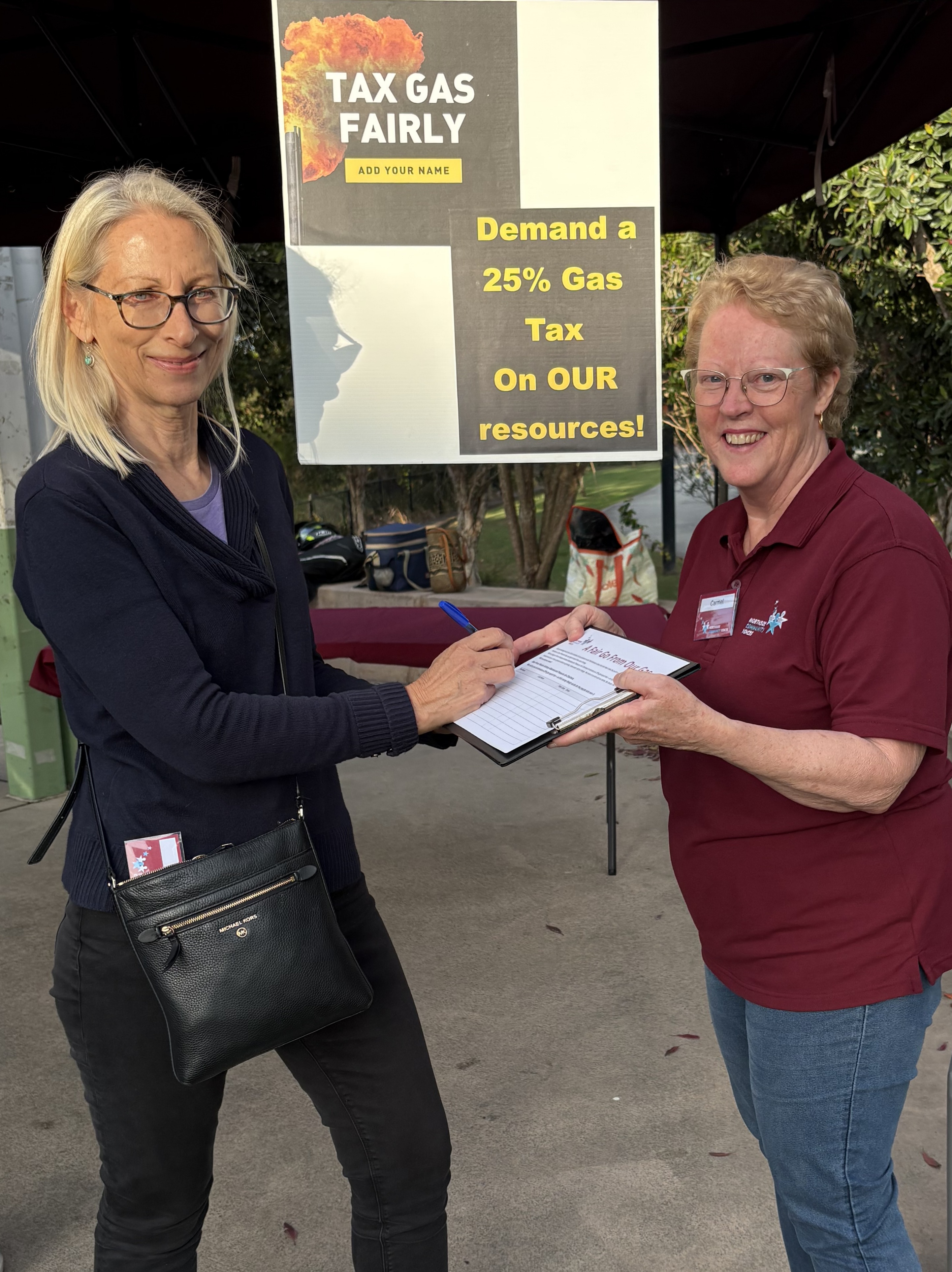 A resident signing the 25% gas export tax petition at an NCV stall in Petrie